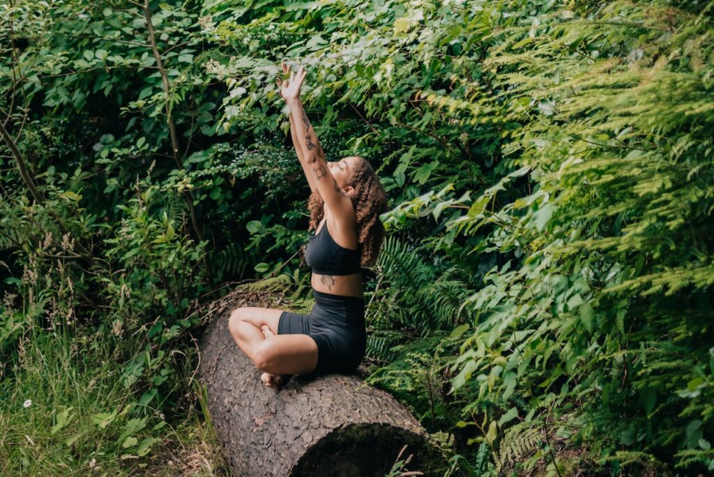Woman in Black Activewear Sitting on a Tree Trunk